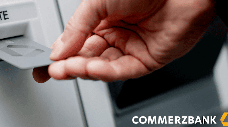 Hand steckt Bankkarte in den Kartenleser eines Commerzbank-Geldautomaten