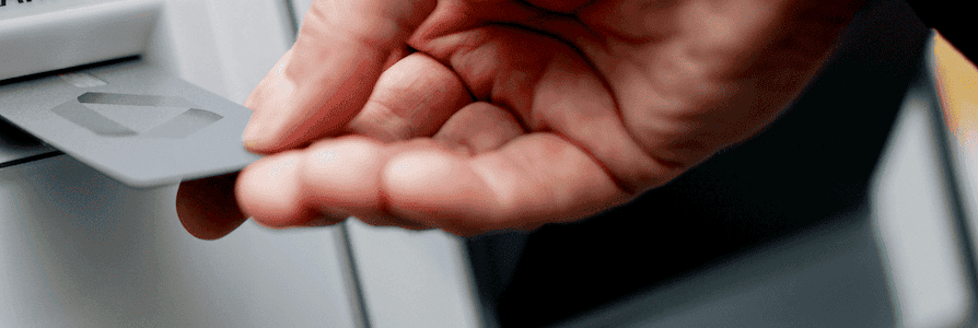 Hand steckt Bankkarte in den Kartenleser eines Commerzbank-Geldautomaten