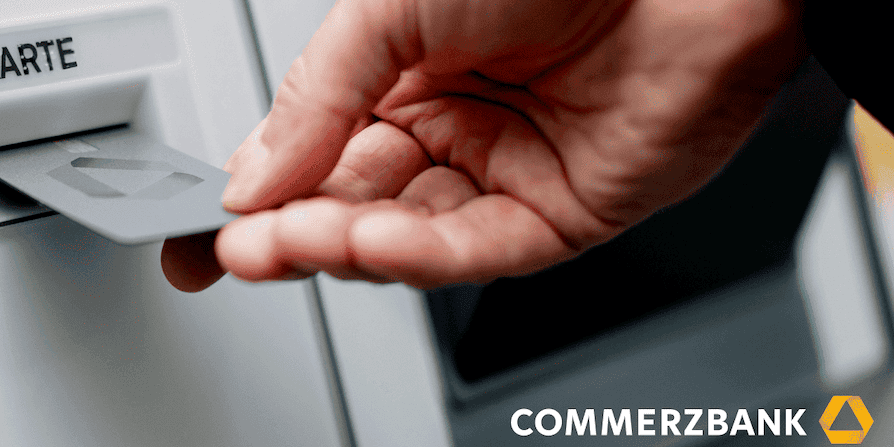 Hand steckt Bankkarte in den Kartenleser eines Commerzbank-Geldautomaten