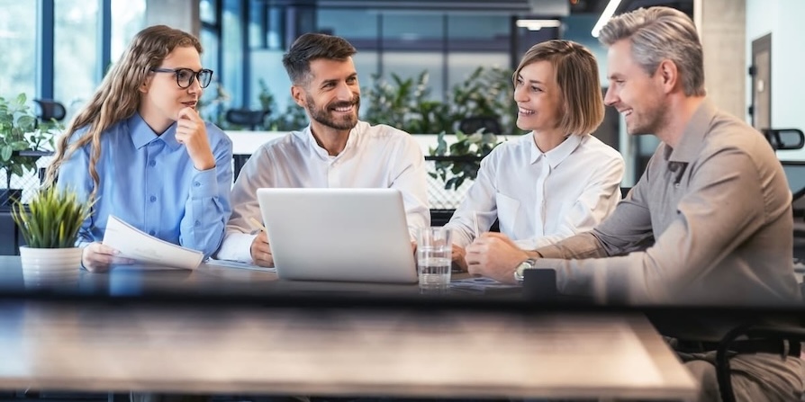 Gruppe von Geschäftspersonen sitzt im modernen Büro und bespricht ein Projekt am Laptop